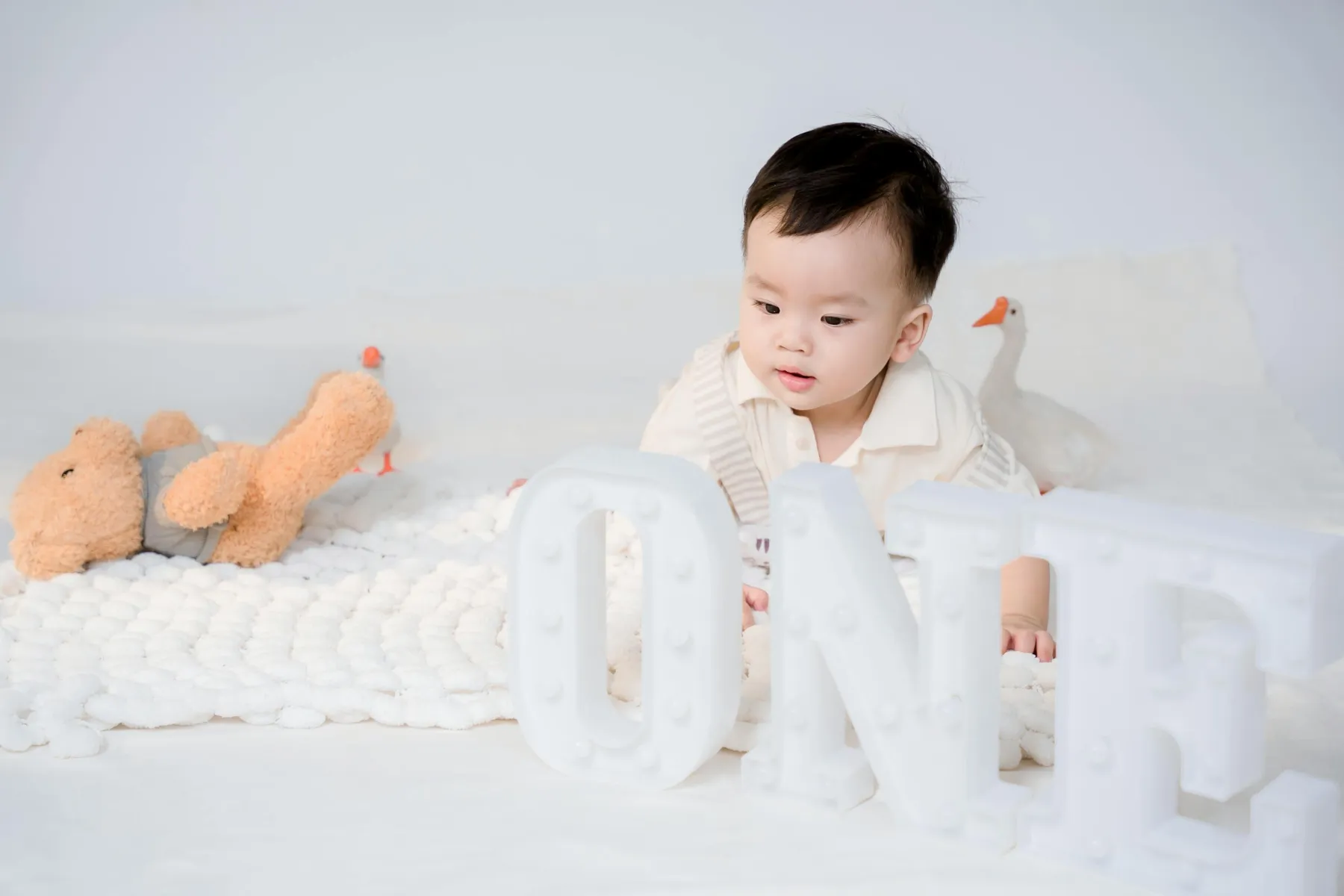 Roczne dziecko z dekoracją „1" podczas sesji roczek w studio fotograficznym