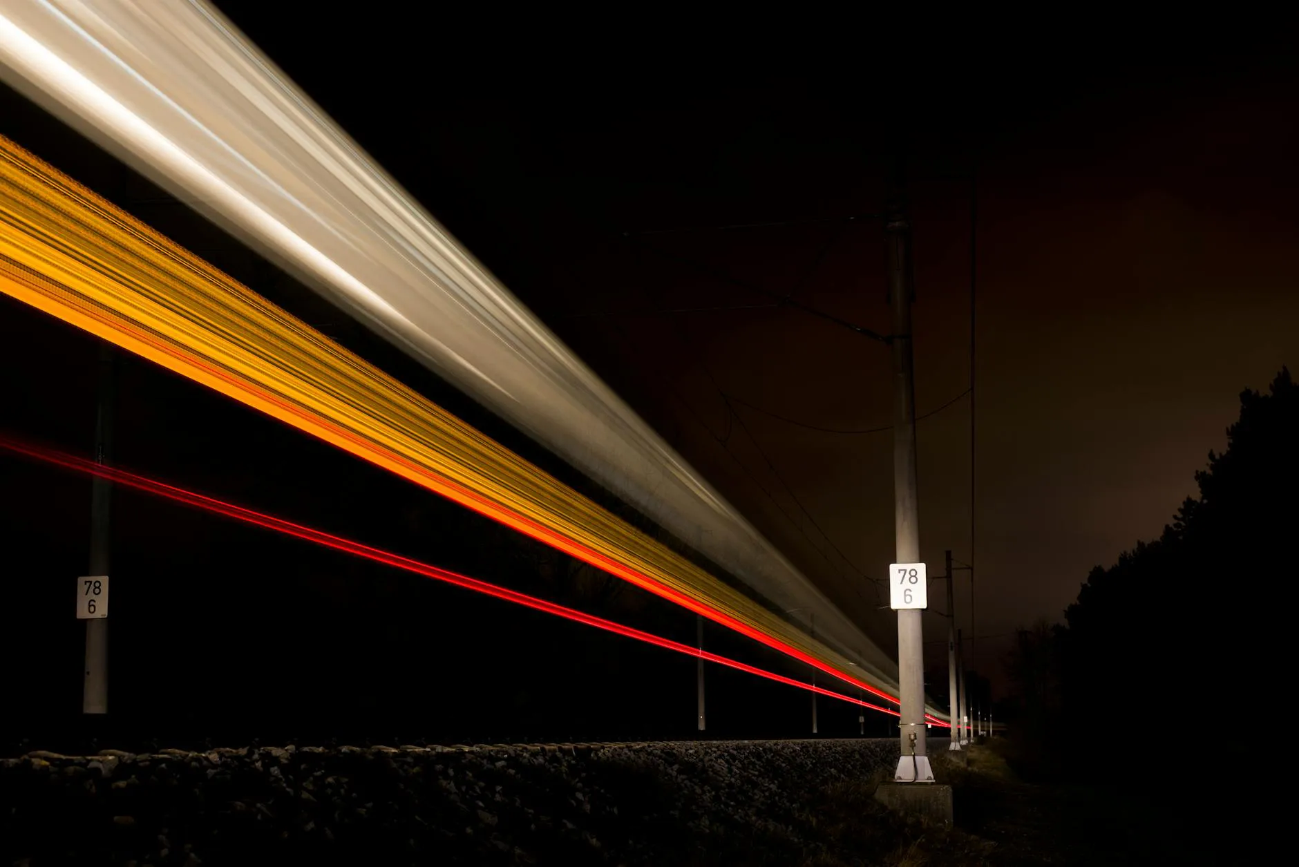Dynamic night train movement captured with long exposure, creating vibrant light trails.