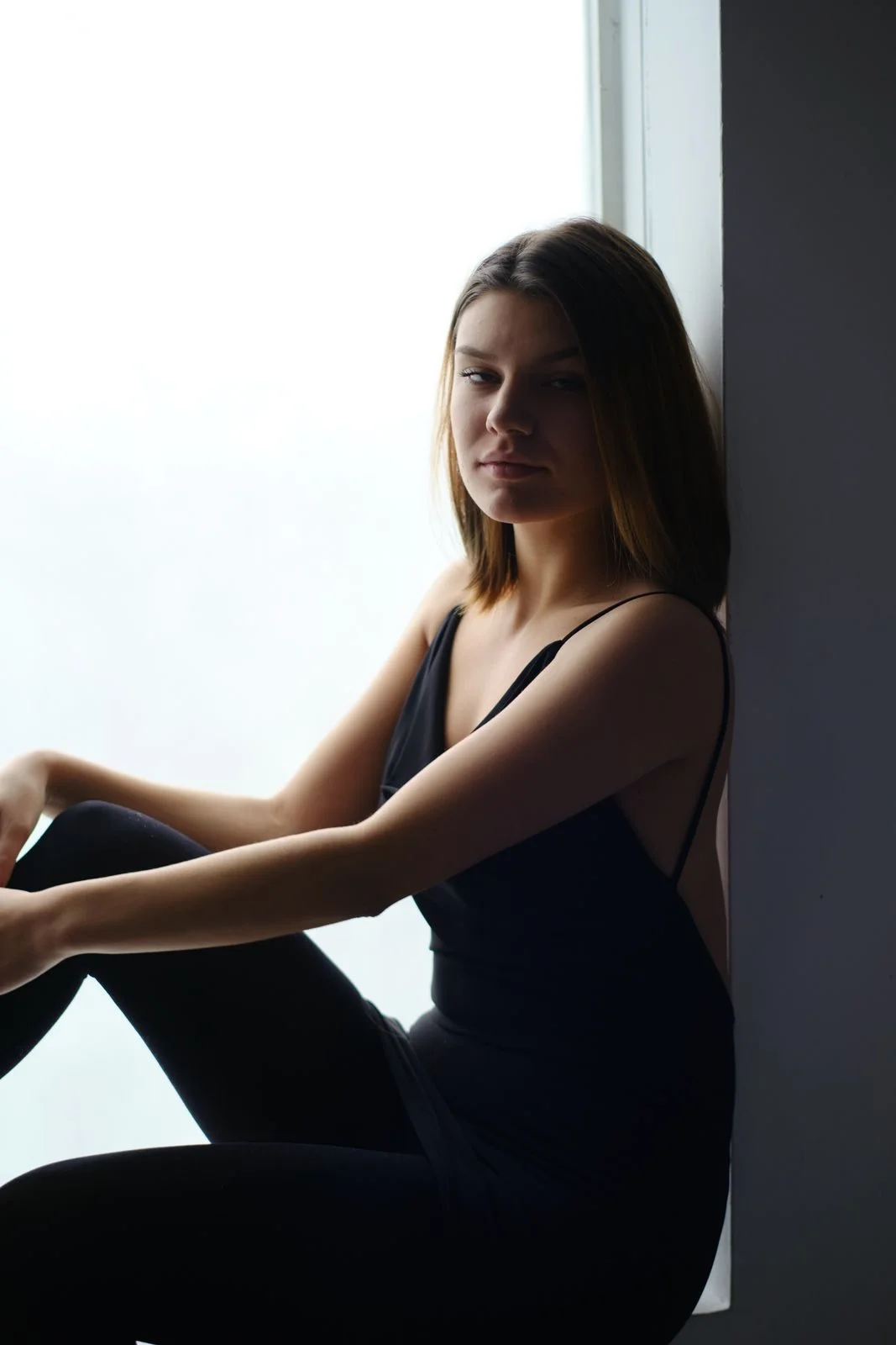 Kobieta w czarnej stylizacji siedząca przy oknie