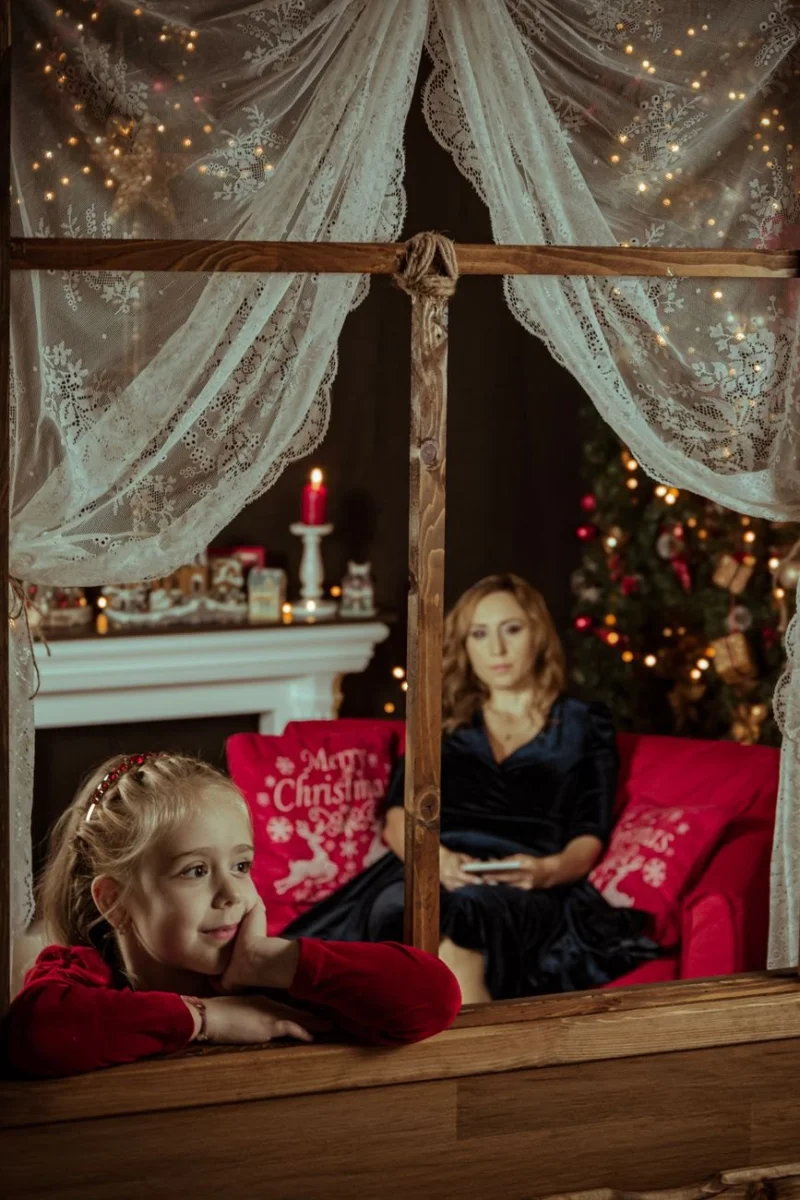 Kobieta z dzieckiem przy kominku w świątecznej scenografii