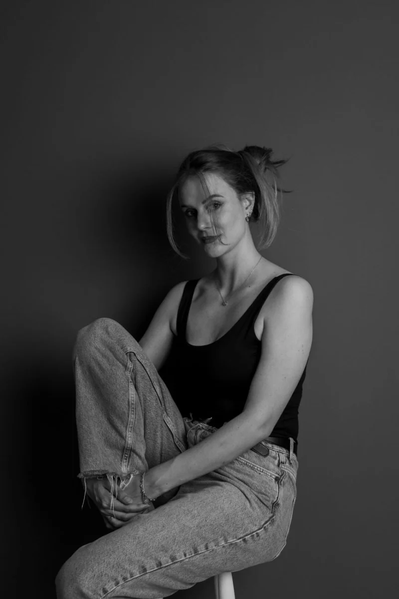 Portret kobiety na krześle w prostej stylizacji na jasnym tle
